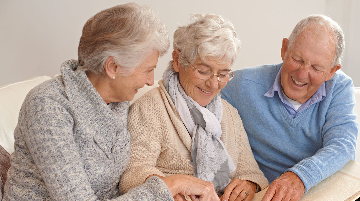 elderly women and man looking through picture books and events at The Delaney at South Shore