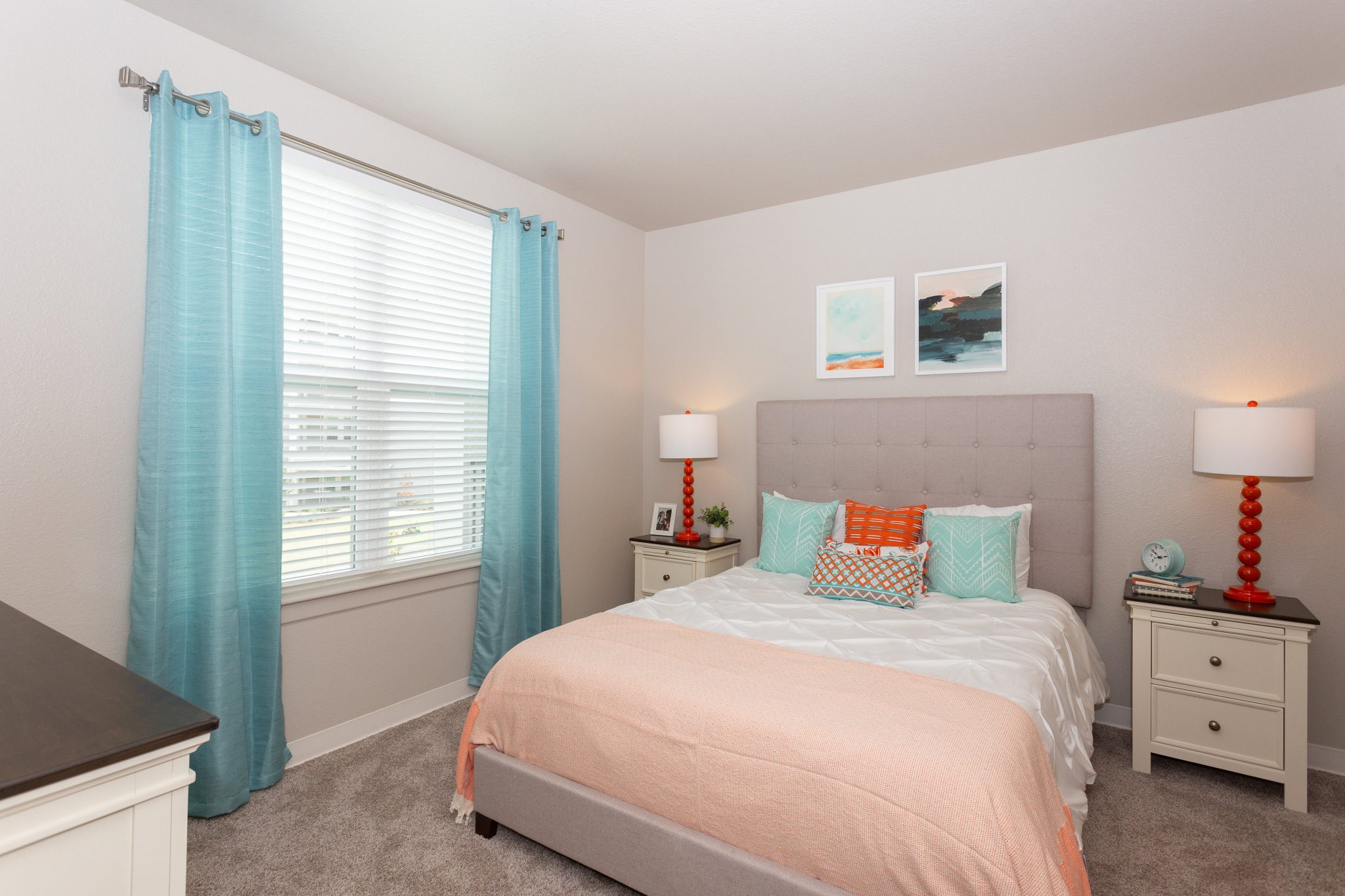 Bright bedroom with modern decor, colorful pillows, and light blue curtains.