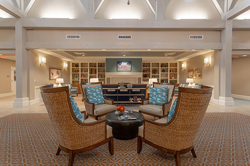 Spacious lounge with wicker chairs, a central table, and a decorative fireplace.