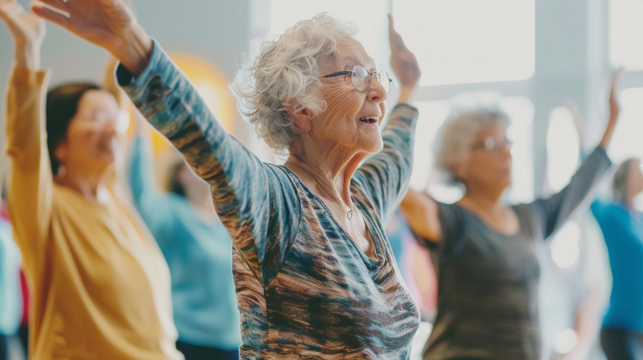 Elderly women engaged in a joyful exercise class with arms raised indoors.